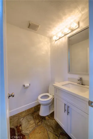 a bathroom with a granite countertop sink a toilet and a mirror