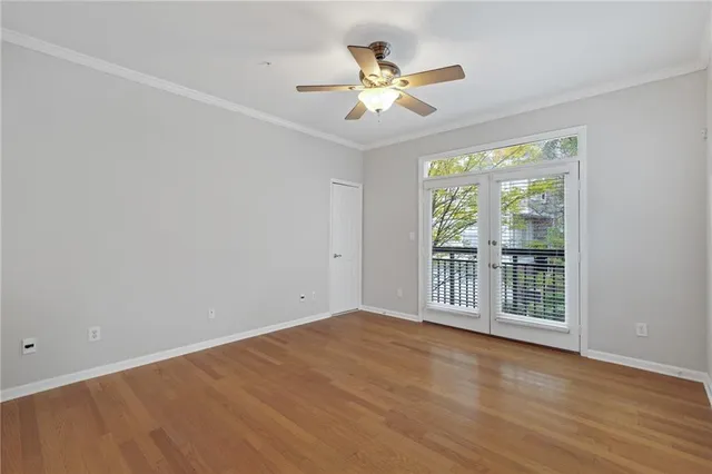 an empty room with wooden floor chandelier fan and windows