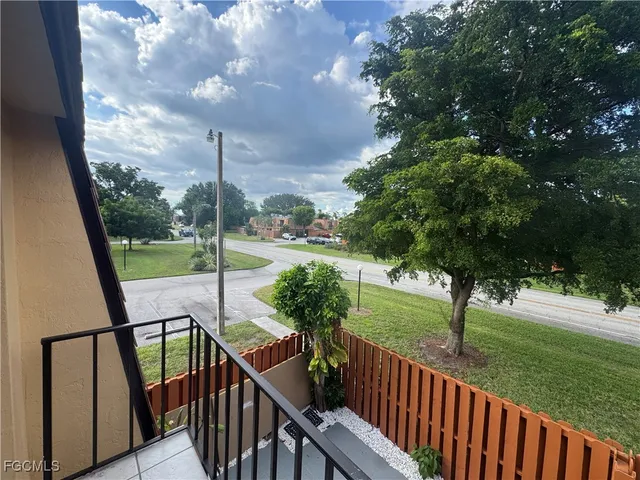 a backyard of a house with plants and tree with wooden fence
