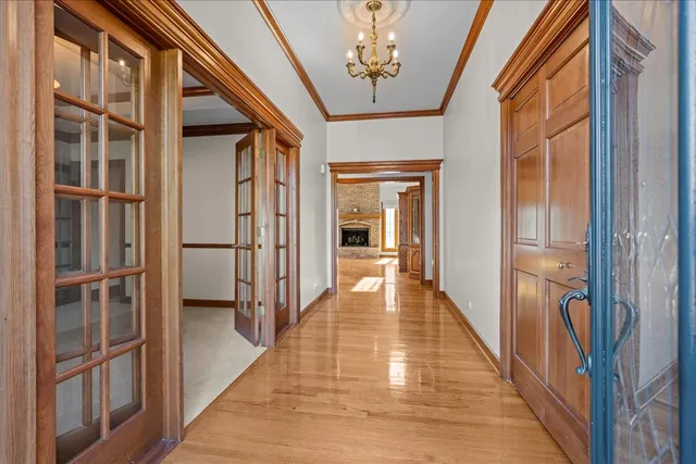 a hallway with wooden floor chandelier and livingroom