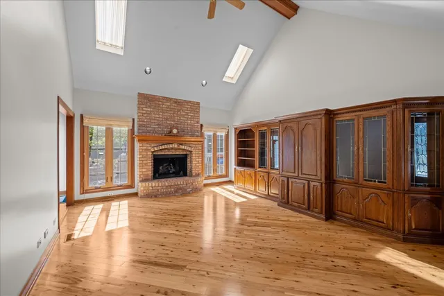 an empty room with wooden floor fireplace and windows