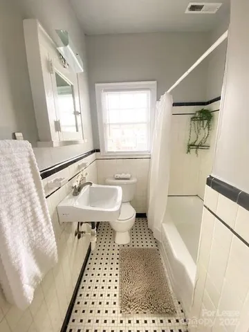 a bathroom with a sink a toilet a mirror and bathtub