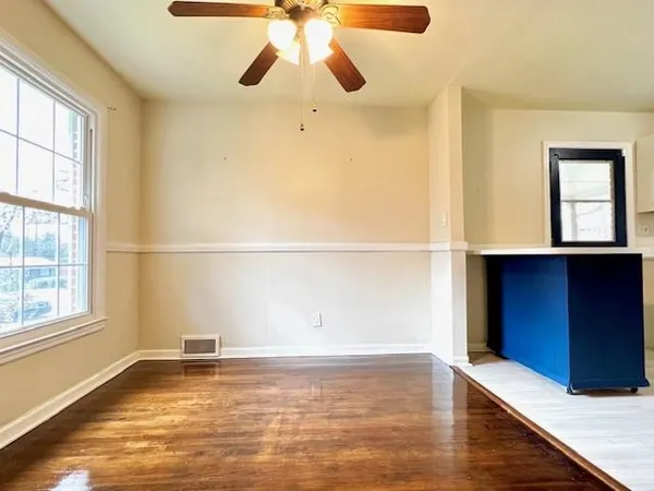 a view of an empty room with wooden floor and a window