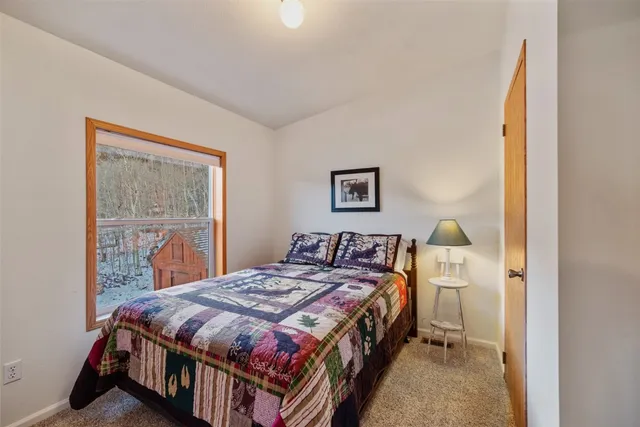 a bedroom with a bed a painting on the wall and a baby crib