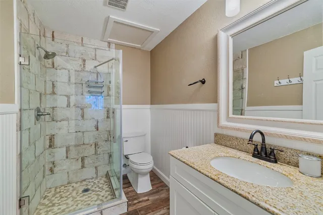a bathroom with a granite countertop sink a toilet and shower