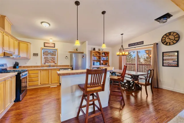 a kitchen with stainless steel appliances granite countertop a stove top oven a sink a dining table with white cabinets and wooden floor