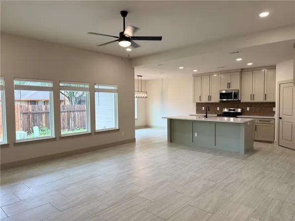 a view of kitchen with stainless steel appliances granite countertop a stove a sink a refrigerator and white cabinets with wooden floor