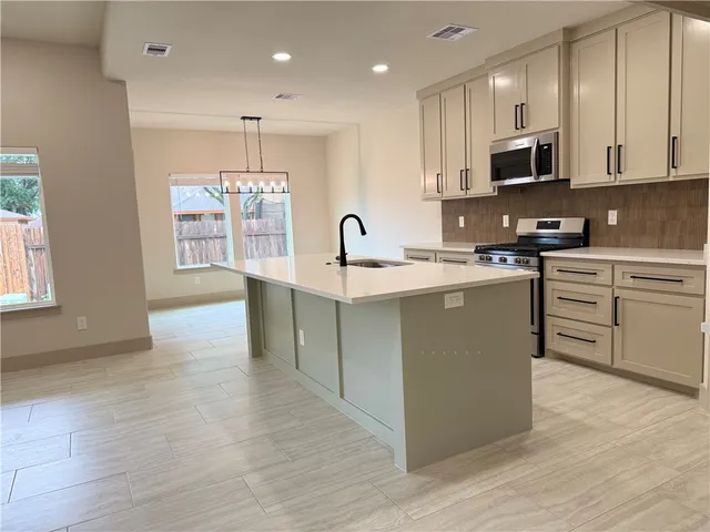 a kitchen with stainless steel appliances granite countertop a stove top oven a sink dishwasher and a microwave oven with wooden floor