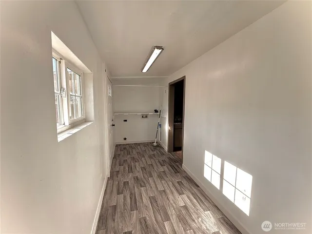 a view of hallway with window and wooden floor