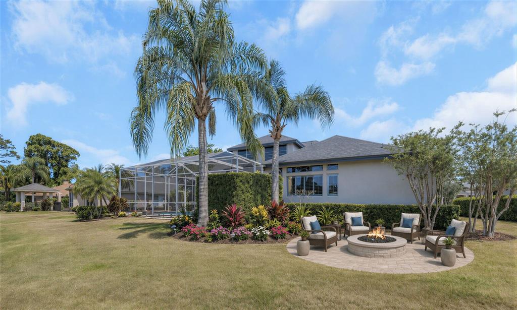 3716 Janus Way Palm Harbor, FL 34685 - Photo 53 of 69 a view of a patio with a table and chairs under an umbrella with palm trees