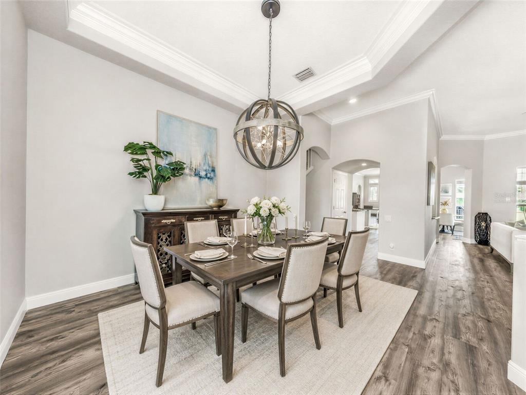 3716 Janus Way Palm Harbor, FL 34685 - Photo 8 of 69 a dining room with furniture a rug a potted plant and wooden floor
