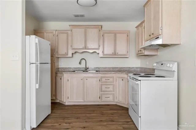 a kitchen with stainless steel appliances granite countertop a refrigerator sink and white cabinets