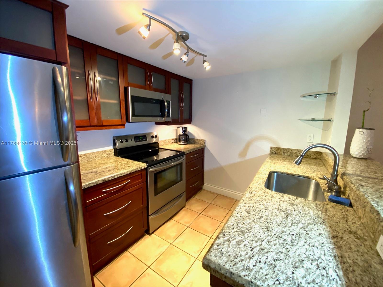 a kitchen with stainless steel appliances granite countertop a refrigerator stove and sink