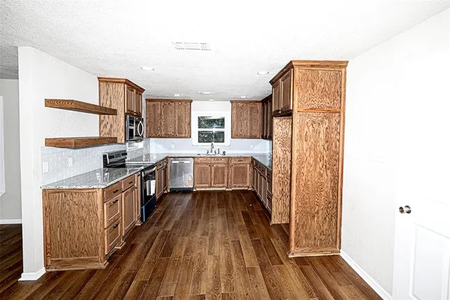 a kitchen with stainless steel appliances granite countertop a sink stove and cabinets