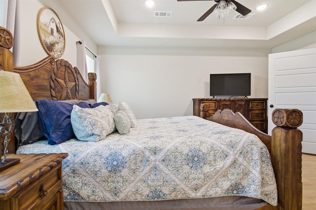 112 Monarch Lane Poolville, TX 76487 - Photo 18 of 37 Spacious bedroom featuring a tray ceiling with recessed lighting, a ceiling fan, and wood-finish flooring