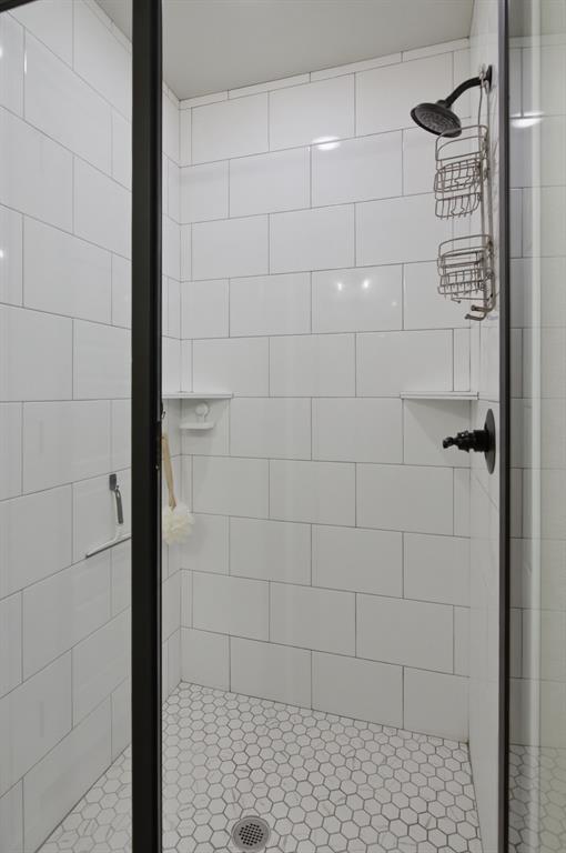 112 Monarch Lane Poolville, TX 76487 - Photo 20 of 37 Walk-in shower with black-framed glass enclosure, white subway tile walls, and hexagon tile flooring