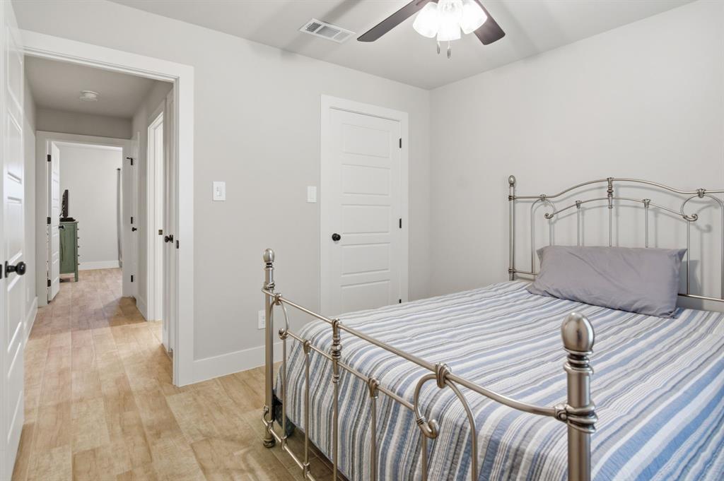 112 Monarch Lane Poolville, TX 76487 - Photo 22 of 37 Room featuring light gray walls, wood-finish flooring, a white five-panel interior door with a matte black knob, and an overhead ceiling fan