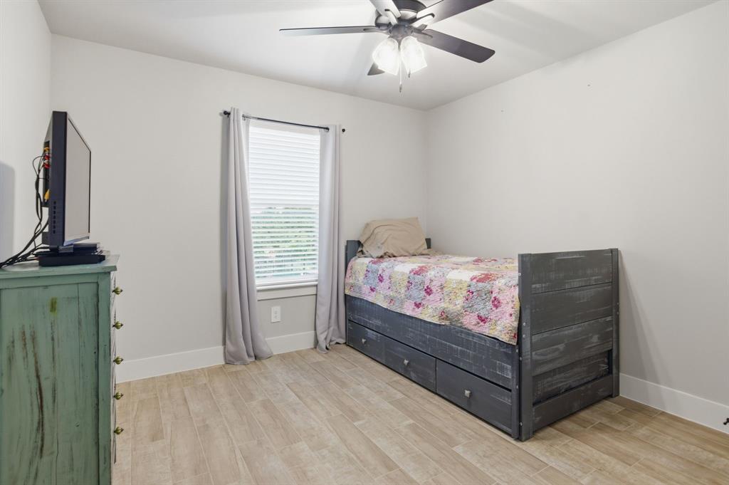 112 Monarch Lane Poolville, TX 76487 - Photo 23 of 37 Bedroom featuring light wood-finish flooring, a window with horizontal blinds, and a ceiling fan with integrated lighting