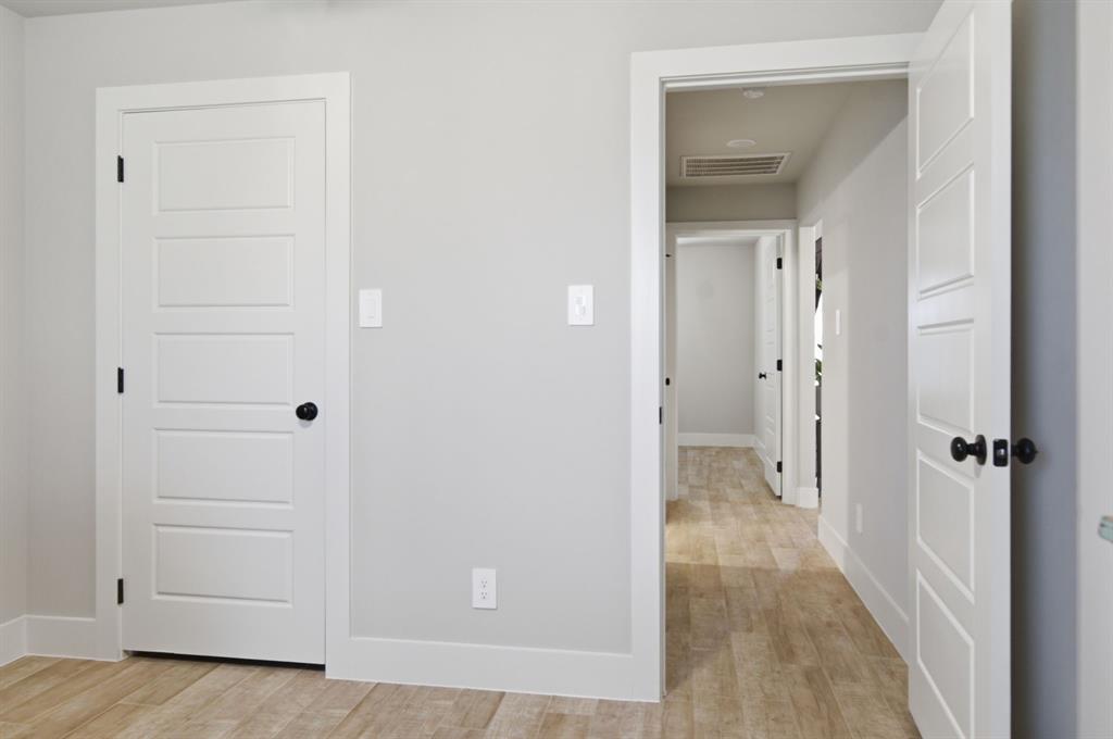 112 Monarch Lane Poolville, TX 76487 - Photo 24 of 37 Interior hallway featuring wood-finish flooring, light gray wall paint, white trim, and white panel doors with matte black hardware