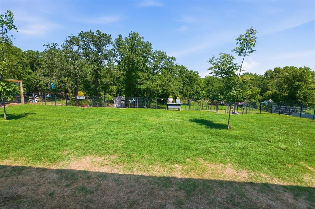 112 Monarch Lane Poolville, TX 76487 - Photo 28 of 37 Expansive grassy yard area featuring a perimeter fence and mature trees
