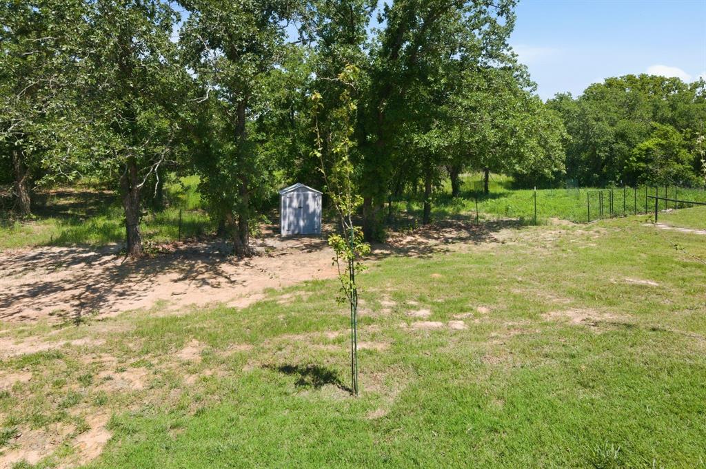 112 Monarch Lane Poolville, TX 76487 - Photo 32 of 37 Expansive grassy area featuring a small, light-colored utility shed