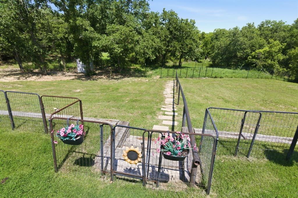 112 Monarch Lane Poolville, TX 76487 - Photo 36 of 37 Expansive green space featuring a stone walkway, metal fencing, and mature trees