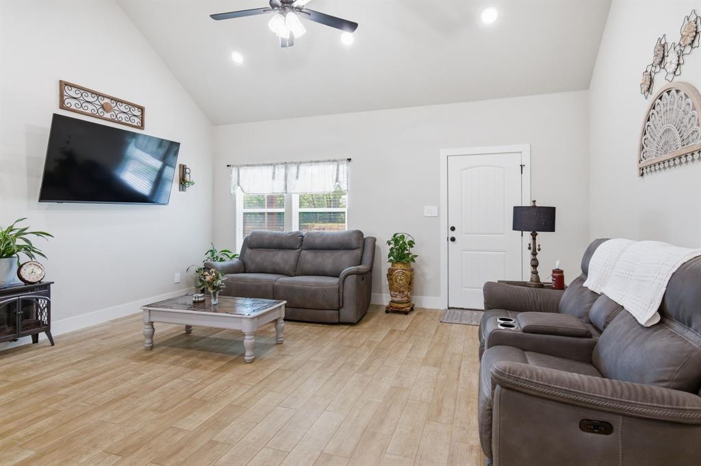 112 Monarch Lane Poolville, TX 76487 - Photo 8 of 37 Spacious living area featuring a vaulted ceiling with a ceiling fan, recessed lighting, and wood-finish flooring