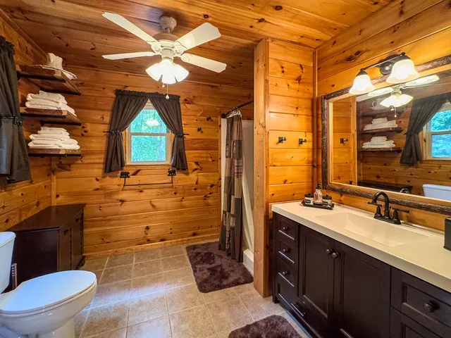 a bedroom with a bed a ceiling fan and a wooden floor