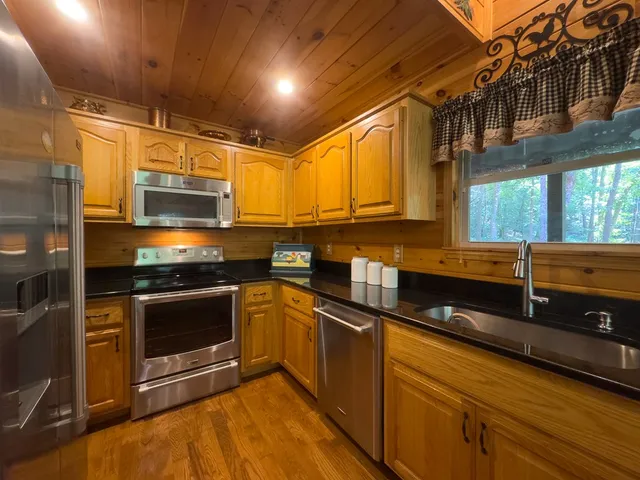 a kitchen with stainless steel appliances granite countertop a stove a sink and a microwave