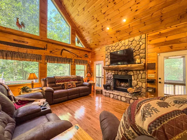 a living room with furniture a fireplace and floor to ceiling windows