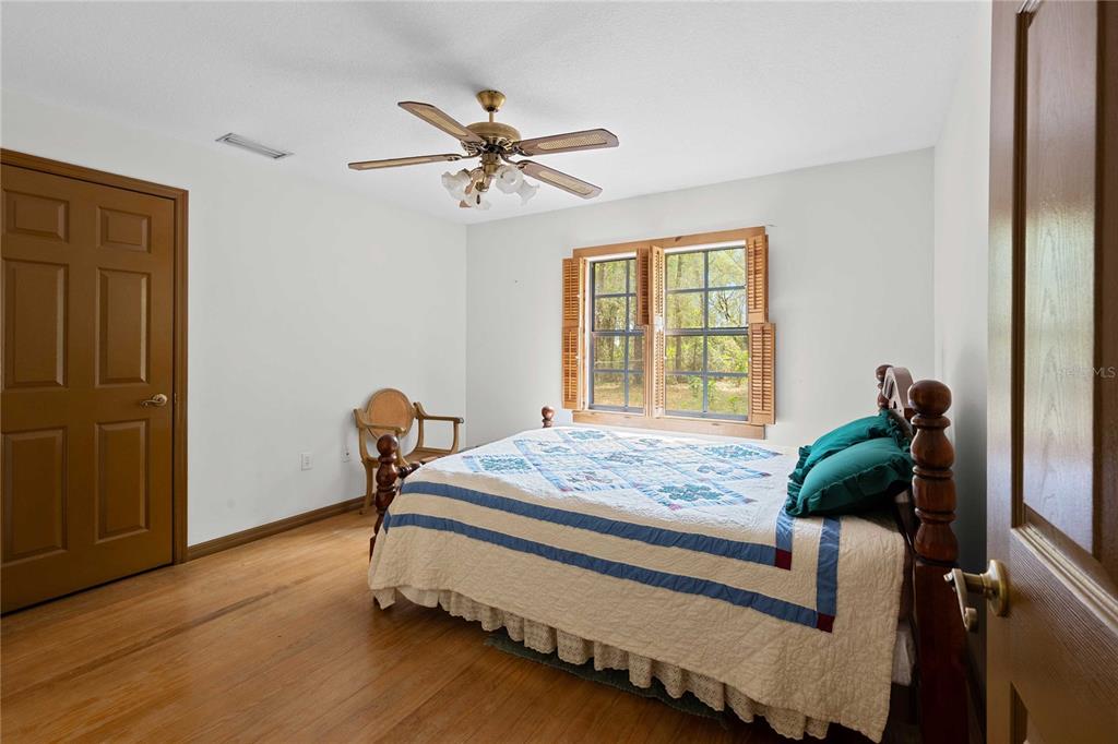 17055 Sweetwater Road Dade City, FL 33523 - Photo 32 of 53 a bedroom with a bed and wooden floor