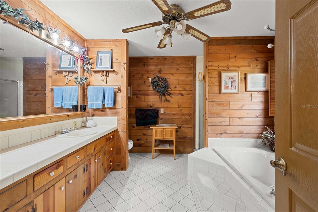 17055 Sweetwater Road Dade City, FL 33523 - Photo 40 of 53 a bathroom with a double vanity sink a mirror and a bathtub