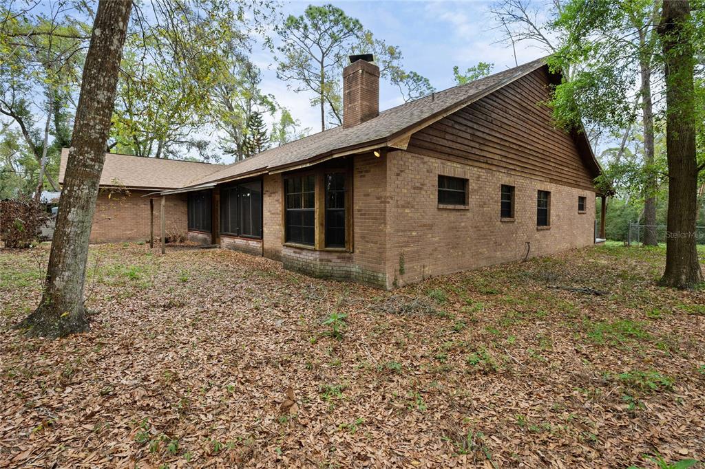 17055 Sweetwater Road Dade City, FL 33523 - Photo 4 of 53 a backyard of a house with large trees and brick walls