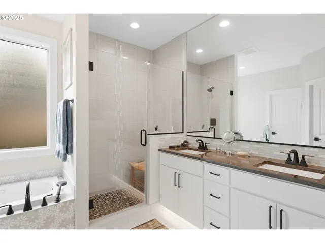 a bathroom with a sink double vanity granite tub shower and a mirror
