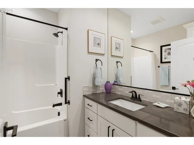 a bathroom with a granite countertop sink a mirror a bathtub and shower