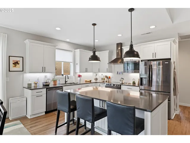 a kitchen with stainless steel appliances kitchen island granite countertop a sink a stove a refrigerator and island