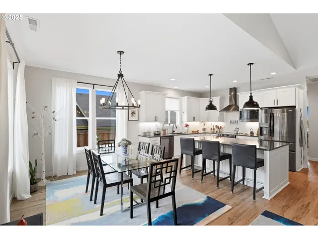 a dining room with stainless steel appliances kitchen island granite countertop a dining table chairs and a refrigerator