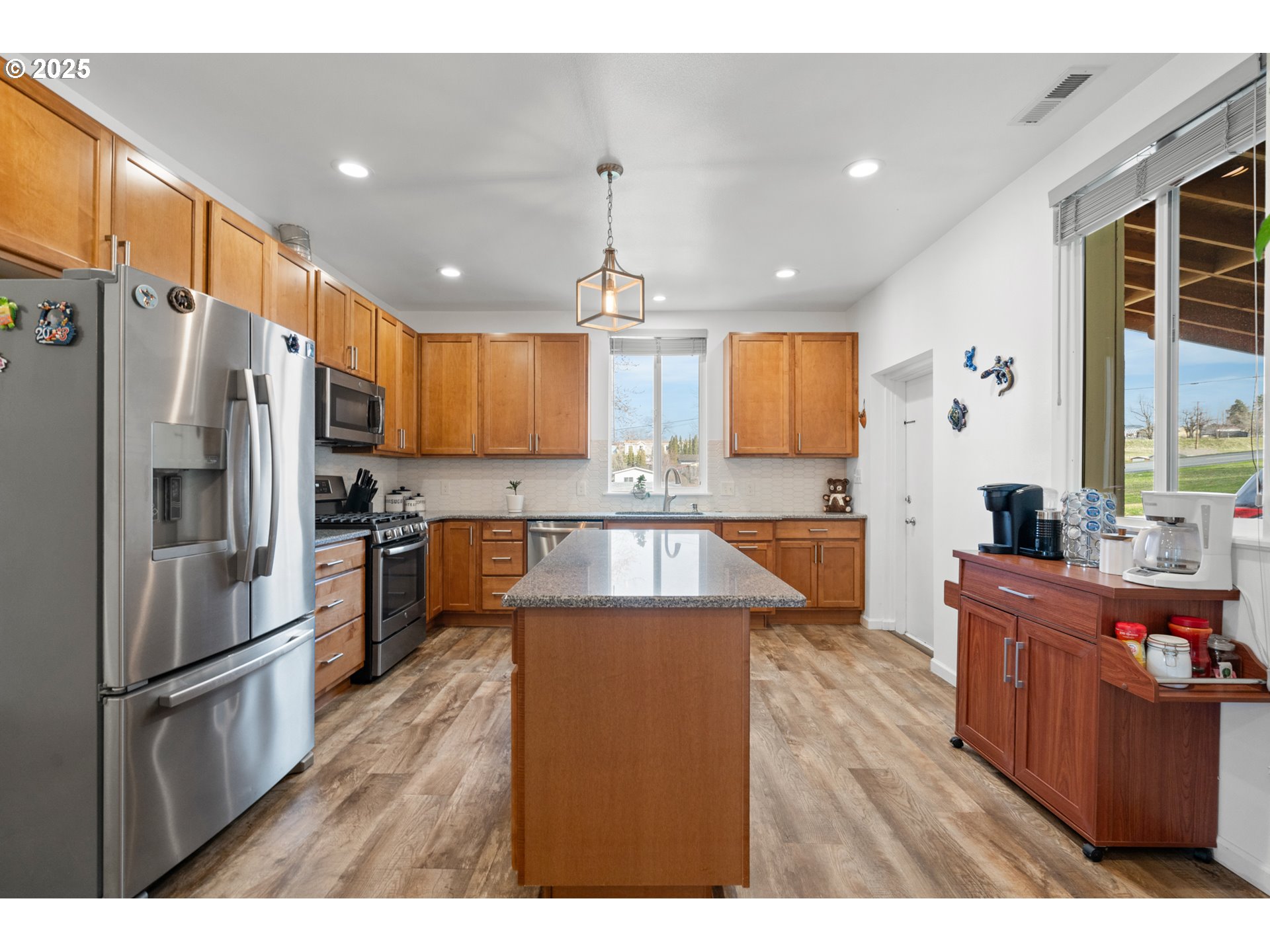 402 East Main Street Weston, OR 97886 - Photo 14 of 36 a kitchen with stainless steel appliances kitchen island granite countertop a refrigerator a sink dishwasher a stove and a dining table with wooden floor