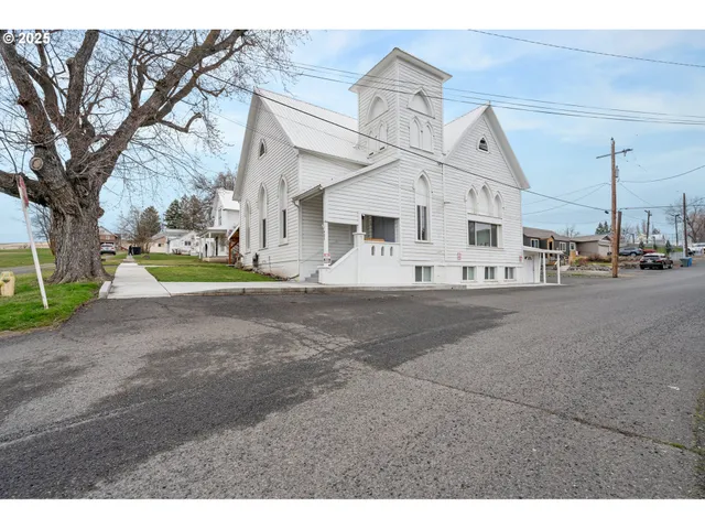 a view of a white house with a big yard and large trees