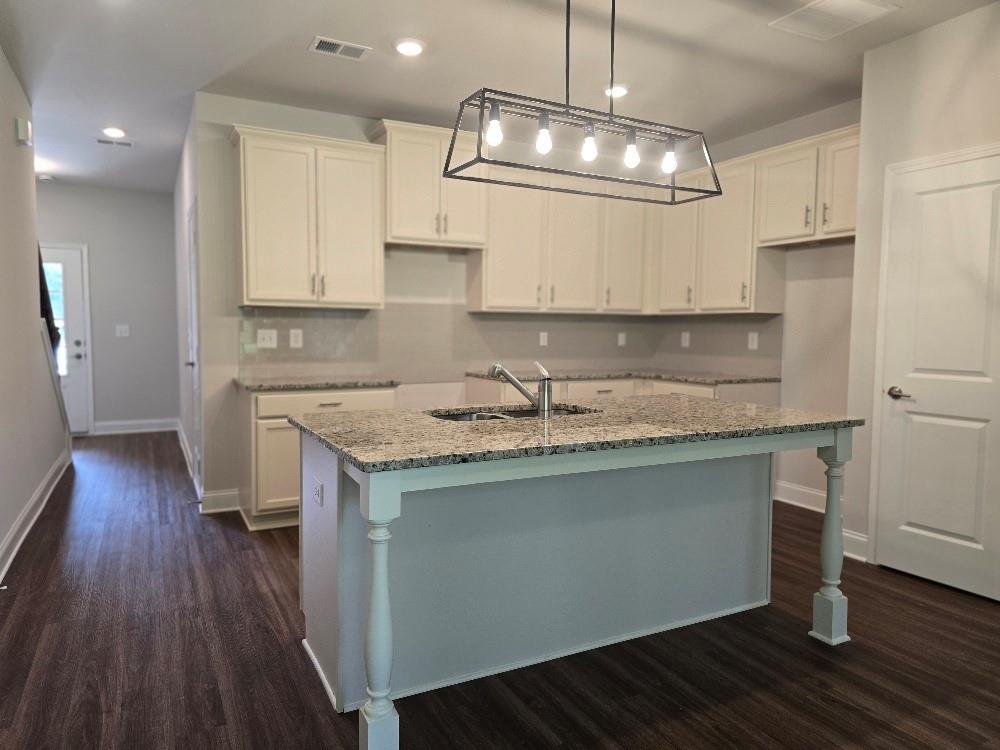 6194 Ripple Way, Unit 86 Atlanta, GA 30349 - Photo 3 of 27 a kitchen with granite countertop wooden floors white cabinets and stainless steel appliances