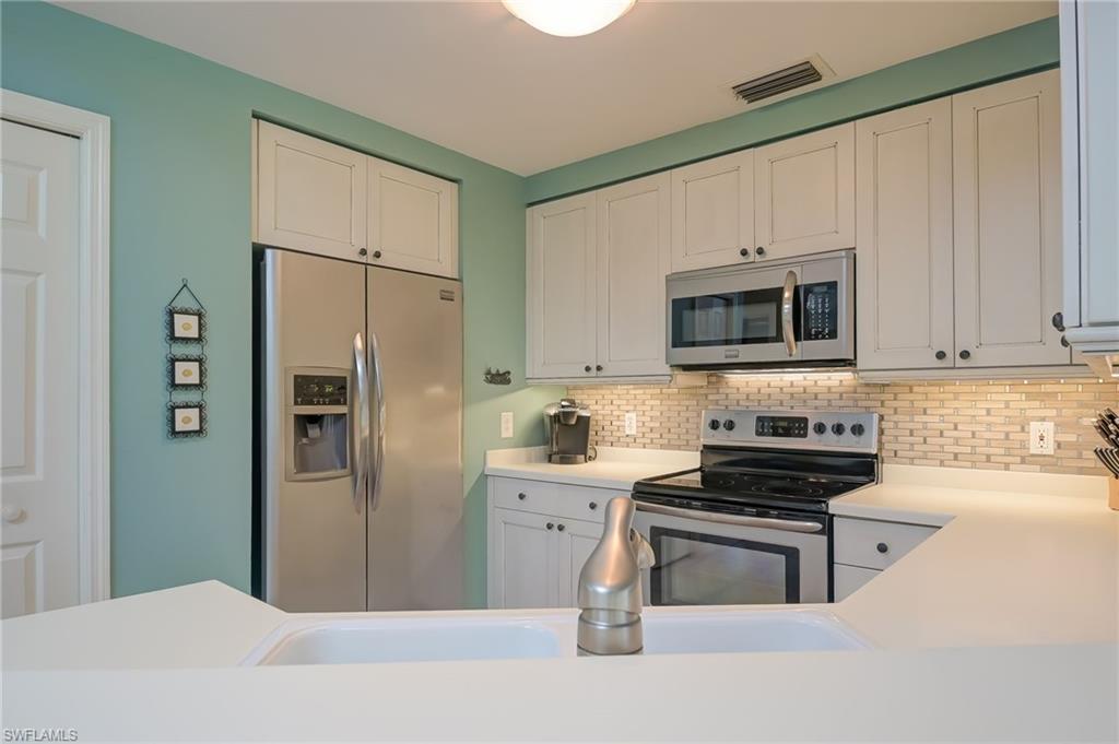 1072 Egrets Walk Circle, Unit 104 Naples, FL 34108 - Photo 13 of 37 a kitchen with stainless steel appliances a refrigerator stove and microwave