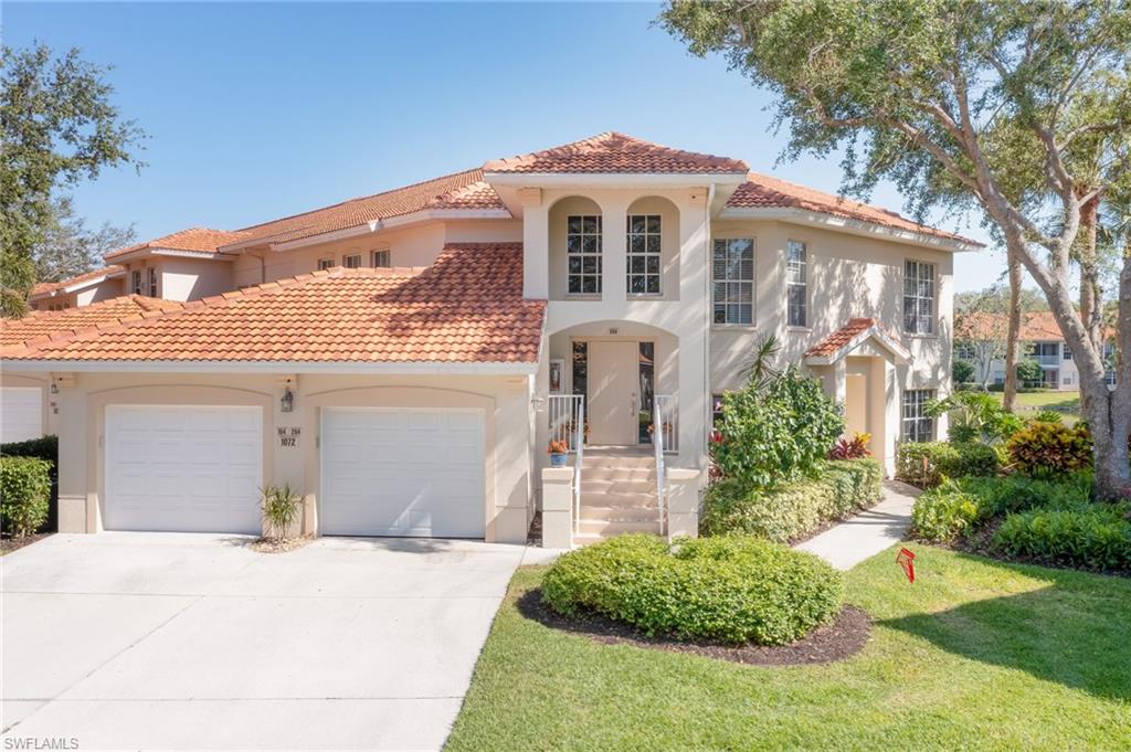 1072 Egrets Walk Circle, Unit 104 Naples, FL 34108 - Photo 2 of 37 a front view of a house with a yard and garage