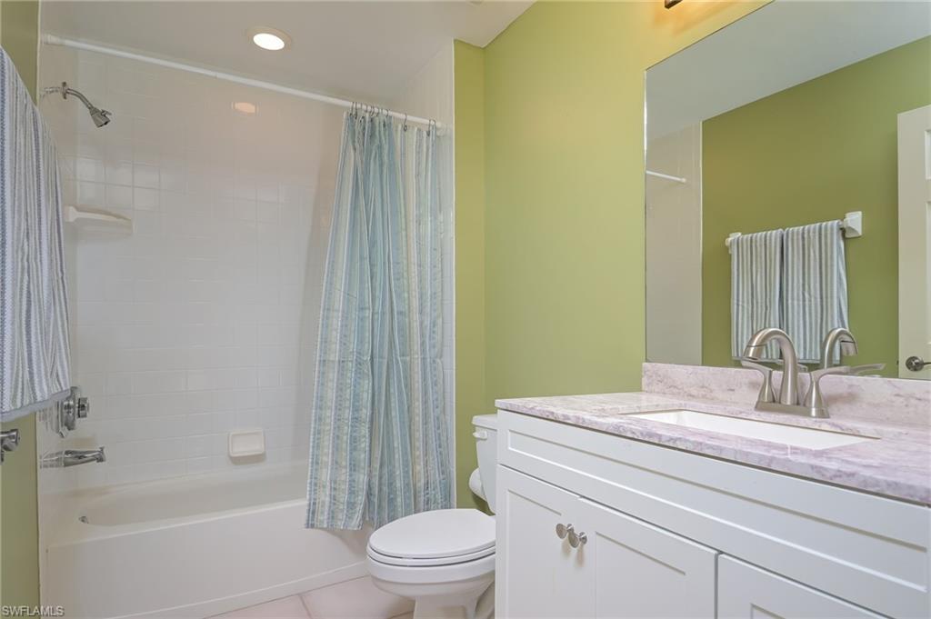 1072 Egrets Walk Circle, Unit 104 Naples, FL 34108 - Photo 23 of 37 a bathroom with a granite countertop sink a toilet and shower
