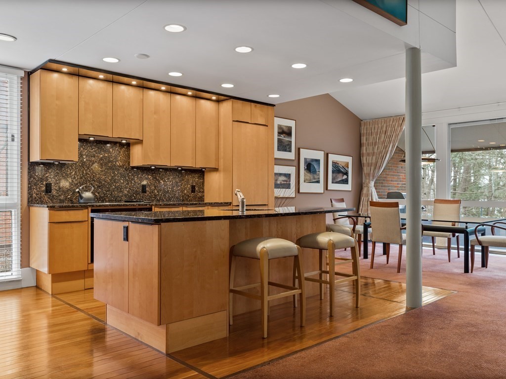 241 Perkins Street, Unit A602 Boston, MA 02130 - Photo 3 of 24 a kitchen with stainless steel appliances granite countertop a table chairs and a refrigerator