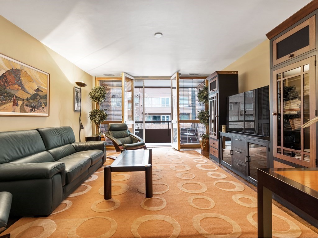 241 Perkins Street, Unit A602 Boston, MA 02130 - Photo 9 of 24 a living room with furniture a flat screen tv and floor to ceiling window