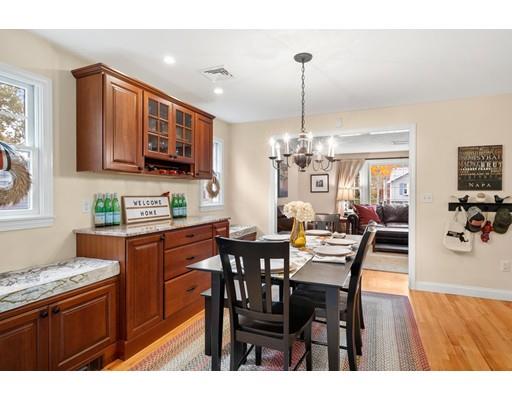 10 Hemlock Road Reading, MA 01867 - Photo 15 of 42 a kitchen with stainless steel appliances granite countertop a sink dishwasher a stove a refrigerator a dining table and chairs with wooden floor