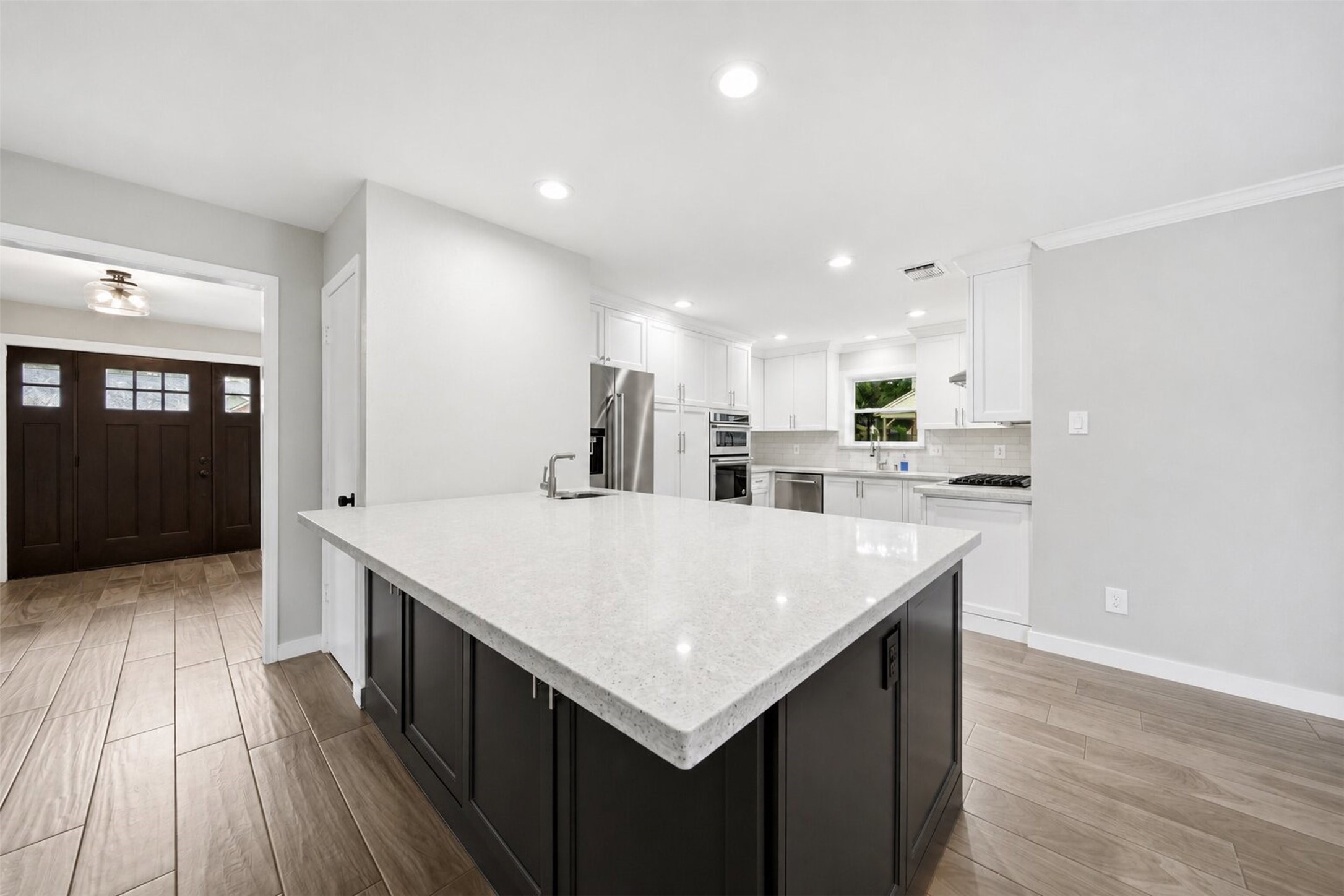 15414 Ripplestream Drive Houston, TX 77068 - Photo 12 of 41 The heart of the home features an impressive open-concept kitchen boasting a massive island with the breakfast bar seating, quartz countertops, and a chic contrasting dark base. This chef's kitchen flows effortlessly into a bright breakfast area and features white cabinetry, stainless steel appliances, and recessed lighting.