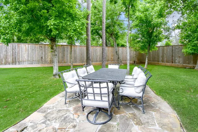 a view of a backyard with table and chairs with wooden fence and plants