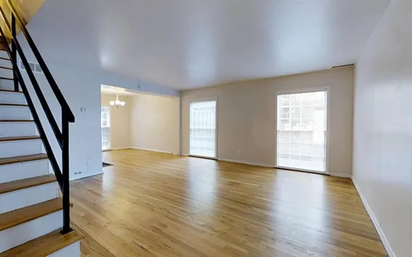 a view of an empty room with wooden floor and stairs