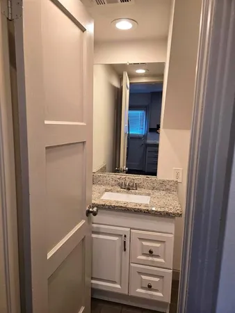 a bathroom with a granite countertop sink and a mirror
